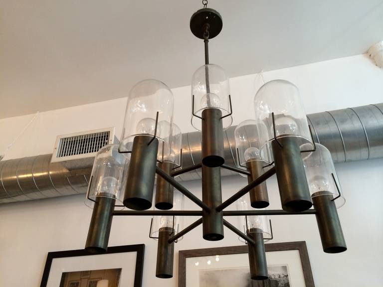 An original 1960s American chandelier designed by Stuart Barnes for Robert Long lighting. Rewired. It has an aged bronze finish and nine hurricane glass shades. It has upward and downward lights with a dimmer.