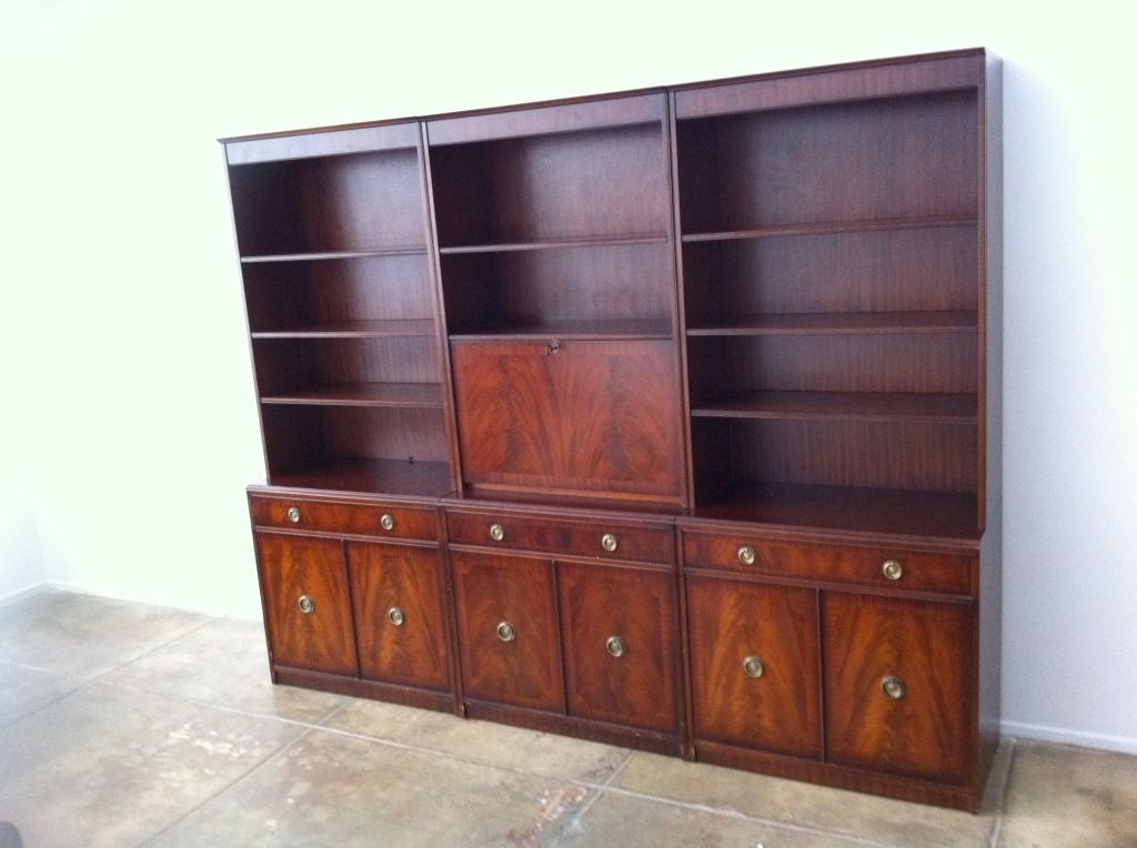 A three part English walnut 1950's Bookcase. Light-up enclosed glass bar cabinet. Three large drawers, Six enclosed interior shelves, ten exterior shelves. Brass fittings.Two keys included