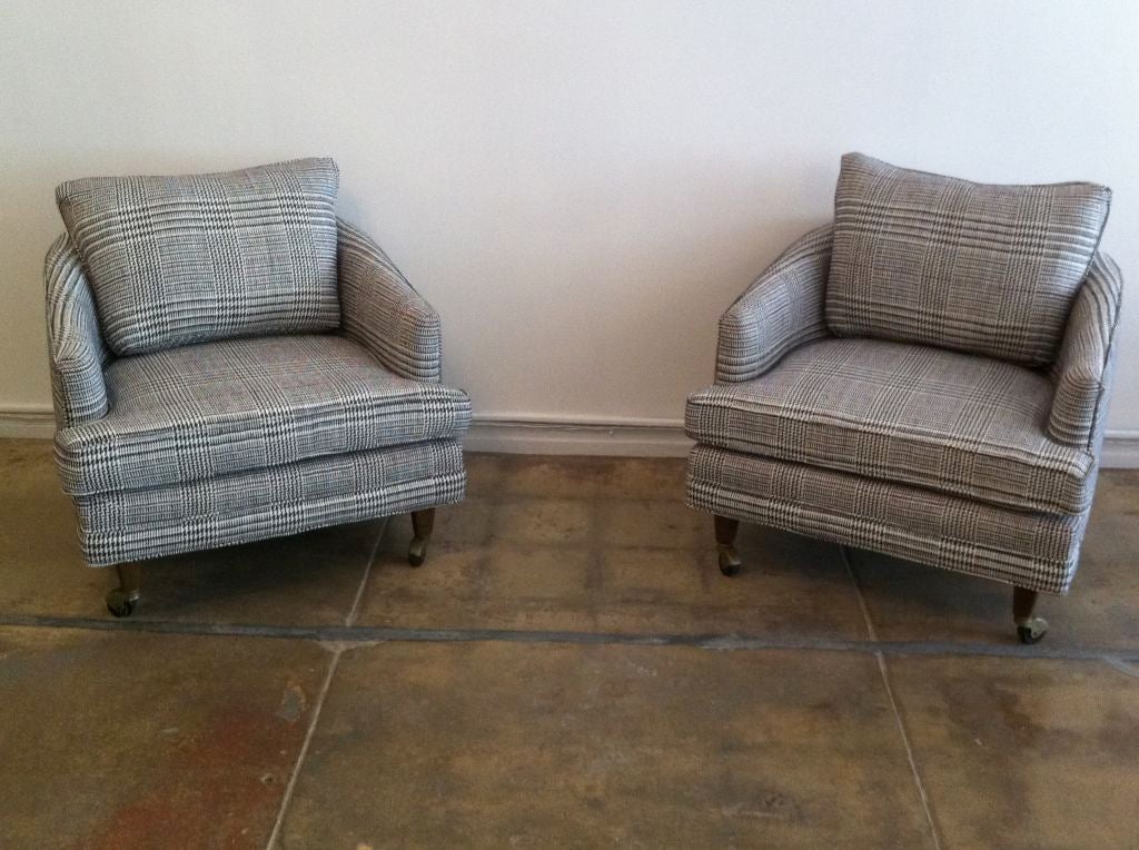 A great pair of newly upholstered wool plaid 1950's barrel club chairs. The fabric is a grey/black/white plaid with a few cranberry stripes.