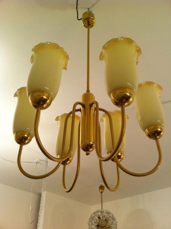 A beautiful 1940s Austrian brass and custard glass chandelier. The fixture has swooping arms holding wonderful blown glass custard shades with ruffled edges.