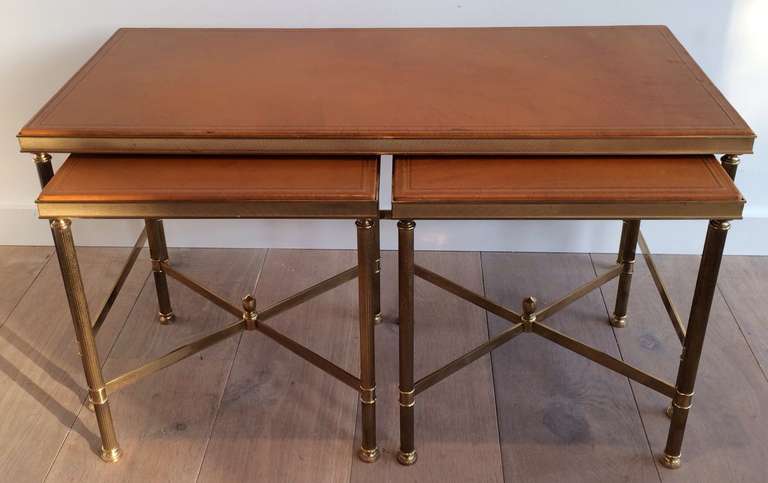 1940s nesting cocktail tables with original leather top and cross stretcher and finial under pair of small tables.