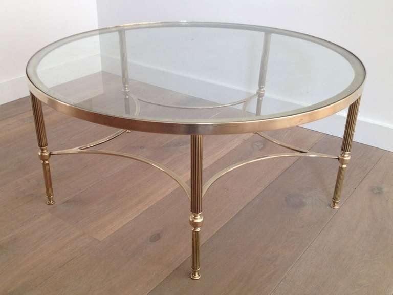 1970s round brass coffee table with glass top. Fluted tapered legs and curved stretcher.