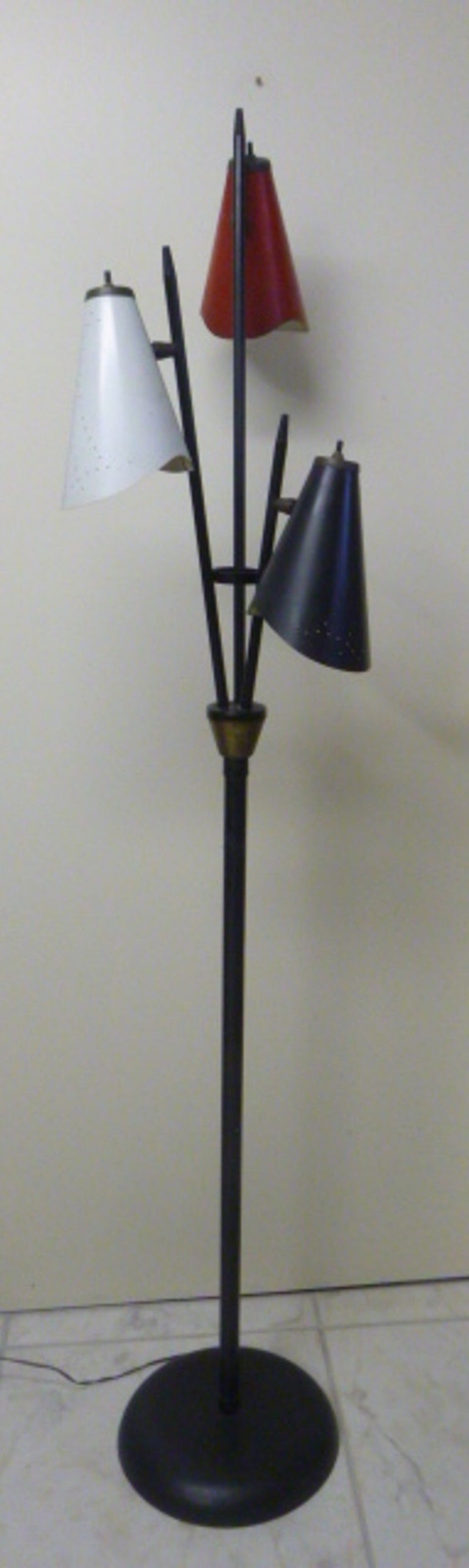 Triennale style floor lamp by Gerald Thurston for Lightolier.  USA, circa 1950.  Features three perforated shades in red, white and black.  Black frame and base with brass detailing.

Dimensions:
62.25 inches H
15 inches W (top with shades)
11