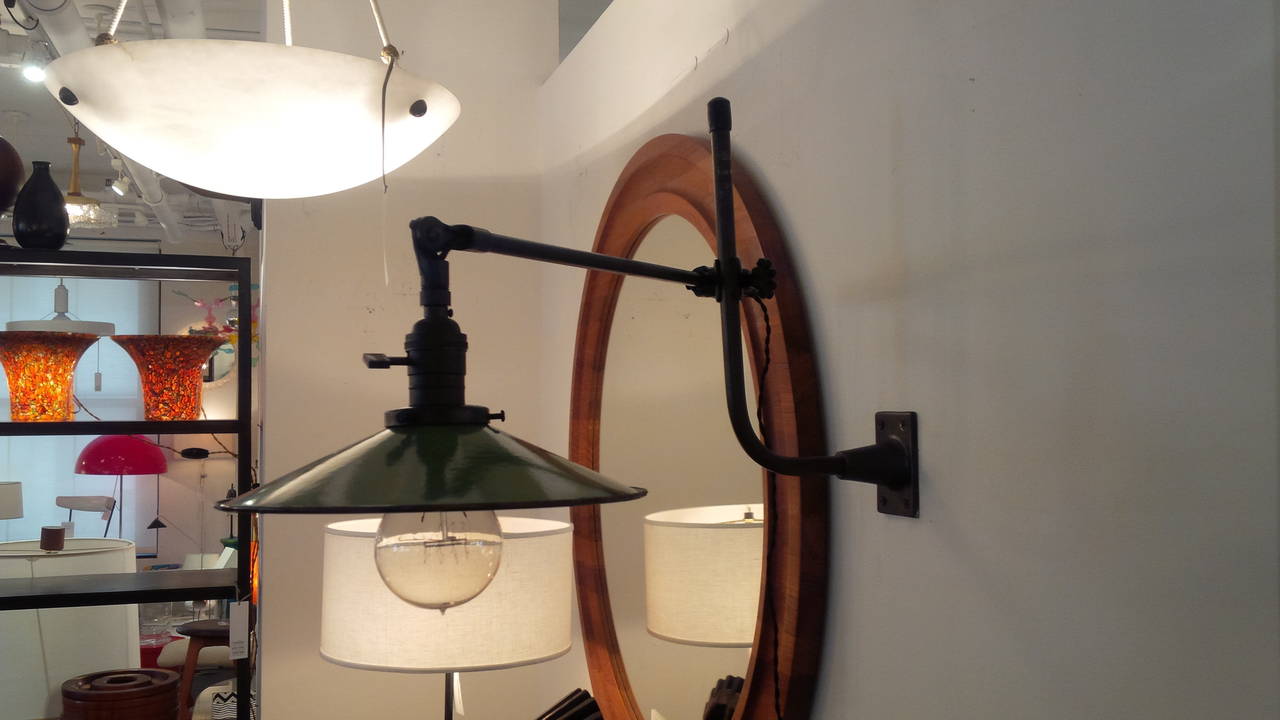 Vintage industrial wall-mount swing-arm lamp by O.C. White. USA, circa 1930.  Metal arms in patinated brass finish with vintage period green enamled metal shade. Includes clear Edison bulb. Custom restored and rewired using French silk twist