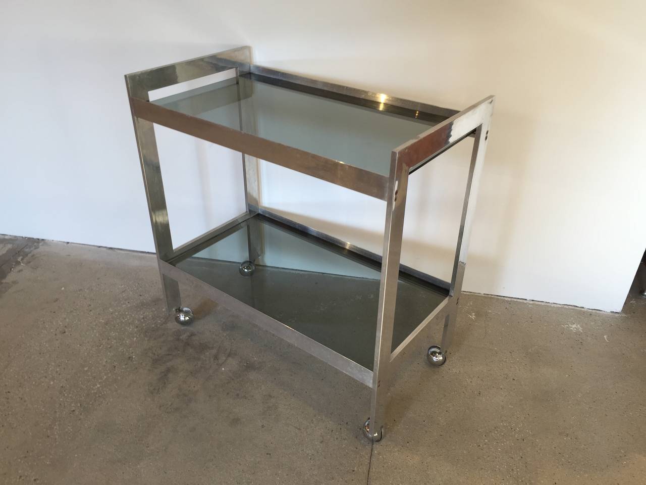Chrome and smoked glass bar cart with two shelves and casters. USA, circa 1970.

Dimensions: 30.25 inches Long x 16.5 Inches Deep x 32 Inches Tall.