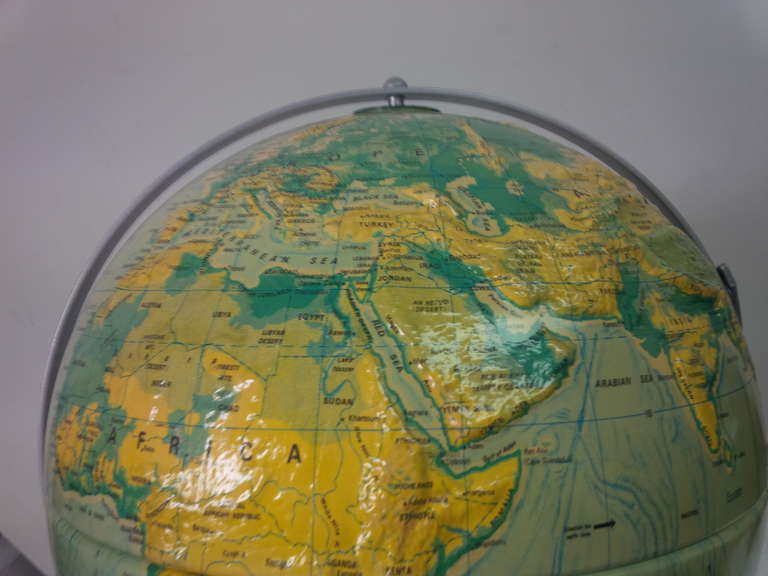 World Relief globe with three-dimensional geographic surface by Nystrom. USA, circa 1960. Features gray metal base for tabletop or wall mount.