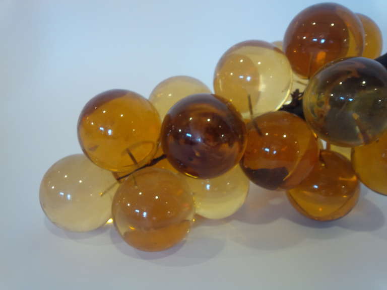 Decorative oversized cluster of grapes made of amber resin with metal stem. USA, circa 1960.