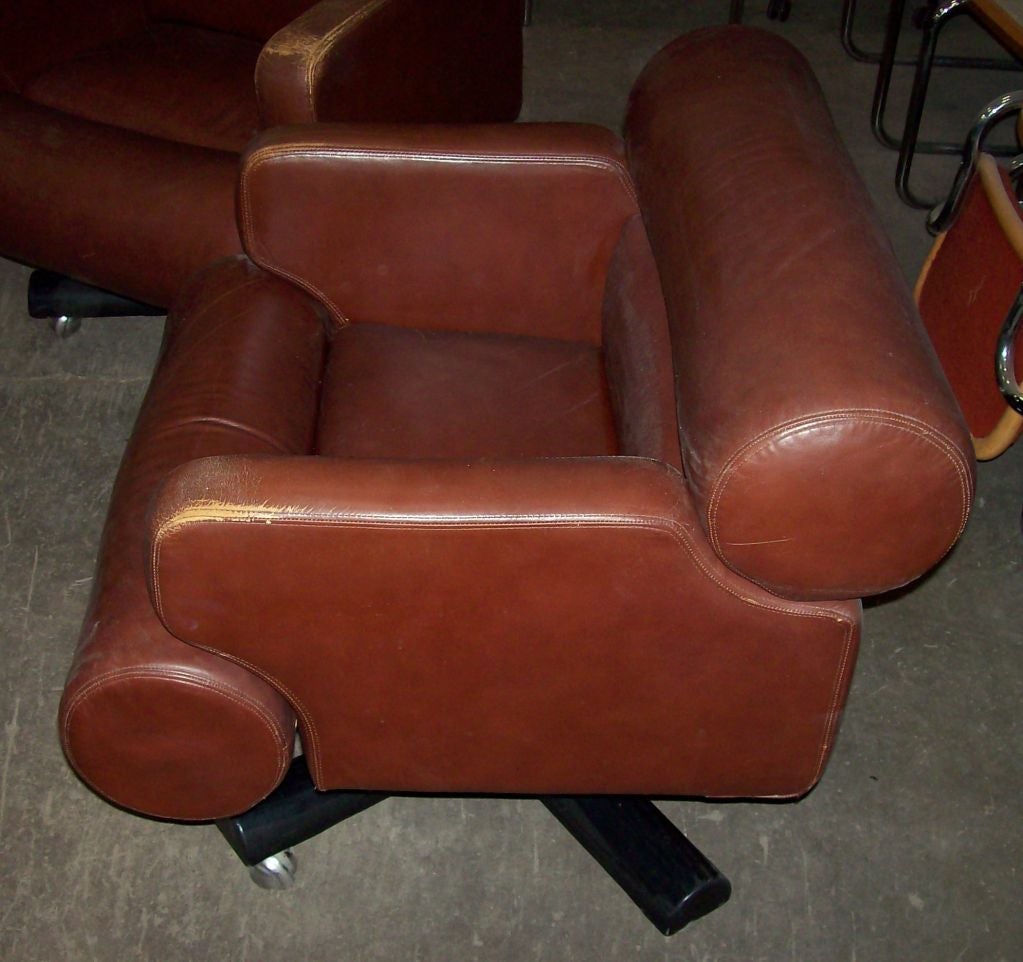 Pair of lounge chairs with swivel base by Joe Columbo.  Italy, circa 1970.<br />
<br />
Sculptural seat upholstered in original brown leather, complemented by four-leg swivel base in black metal with casters.<br />
<br />
Dimensions:<br />
29