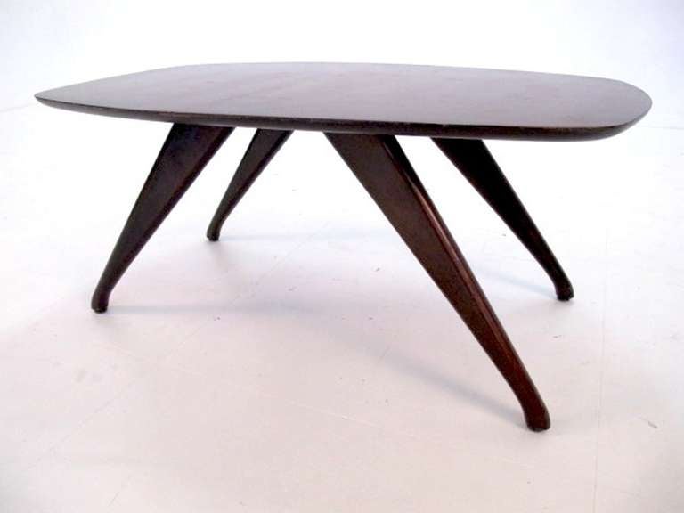 A modernist wood coffee table with four legs.  USA. circa 1950.

Refinished in a dark brown/chocolate finish.