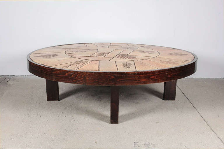 Round ceramic tile top low coffee table with dark-stained French oak base by Raymond Le Duc for VALLAURIS. Signed on one of the tiles. France, circa 1950.

Features botanical leaf and fern relief design on earth tone tiles.