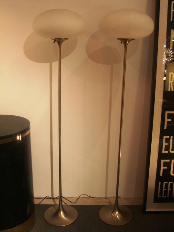 Pair of brushed metal floor lamps with mushroom-shaped frosted glass globe shades by Laurel Lamp Company. USA, circa 1960.<br />
<br />
Lamps feature a tulip-shaped base; on/off switch on globe holder.<br />
<br />
Priced as a pair; please