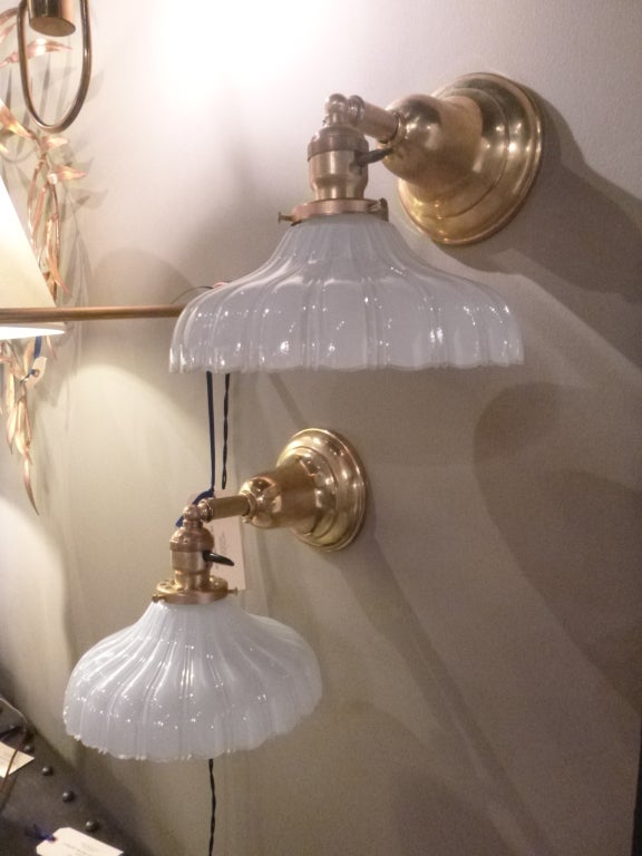 Pair of brass wall sconces with scalloped milk glass shades. USA, circa 1930.  Wall lights and shades are both vintage.

Restored and rewired with new sockets. Each sconce takes one standard base bulb (60 watts max).