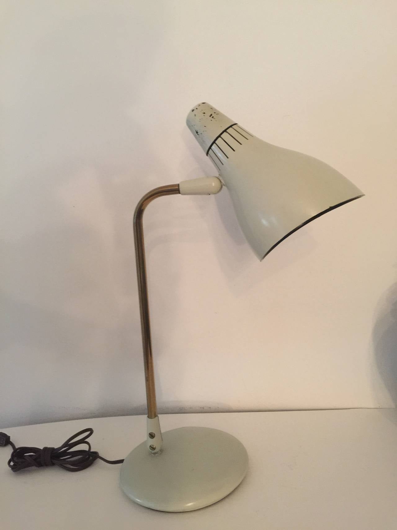 Bone white metal and brass desk lamp by Gerald Thurston for Lightolier, USA, circa 1960. Features a cone-shaped metal shade and round base with antiqued brass arm. Adjustable shade and arm. On/off switch is built into shade top. Wired for U.S.;