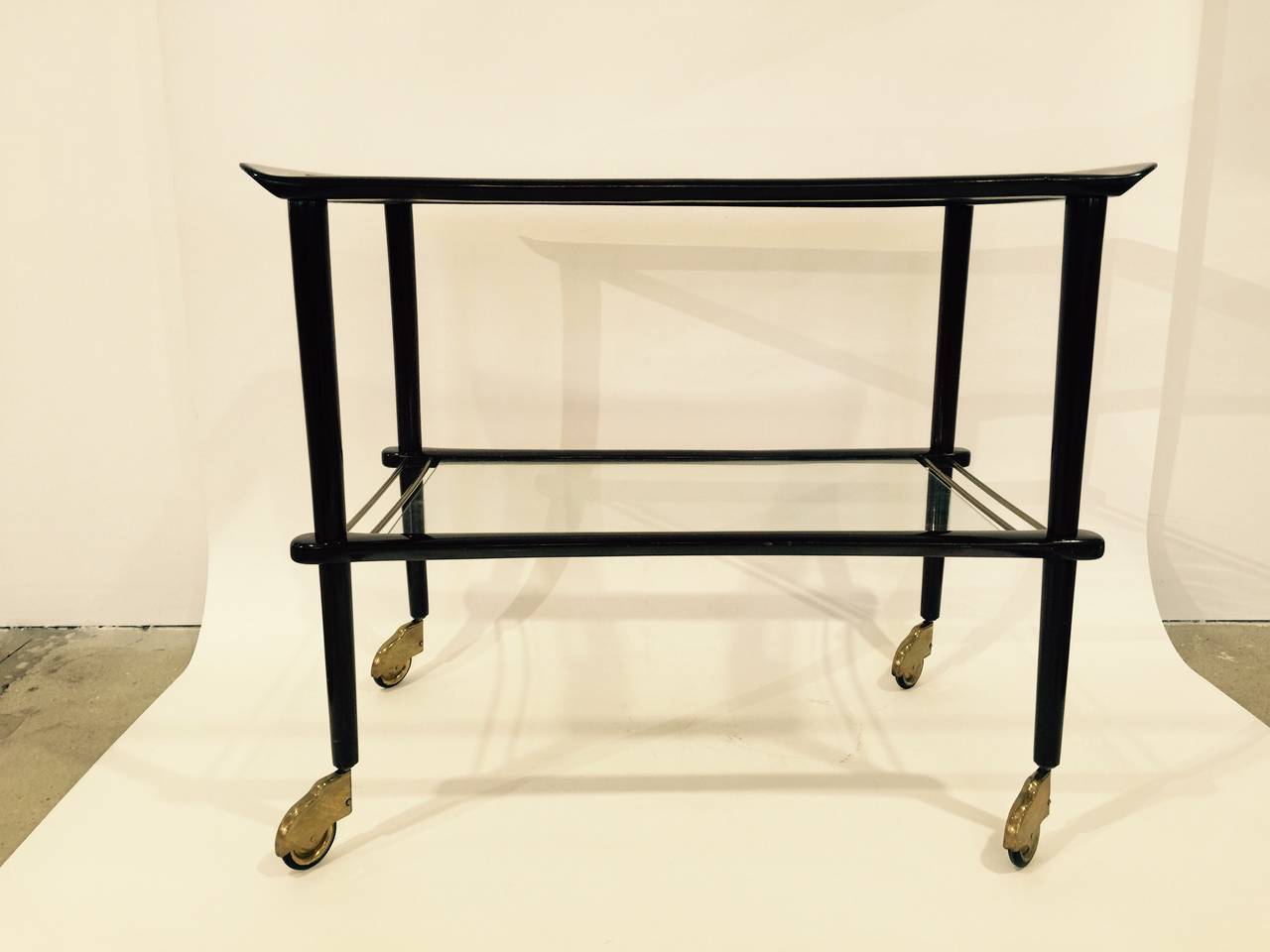 Elegant lacquered wood and glass bar cart on casters.  Italy, circa 1950.  

Originally purchased from Italian furniture dealer Gaspare Asaro.  Features dark brown lacquered finish with two shelves.  Please view our other listings for a matching set