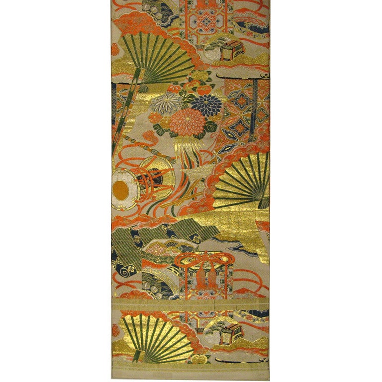 Japanese silk brocade maru obi (woman's kimono belt) from the Meiji period (circa 1910). Maru obis are the most formal of the obis and were used for weddings. Patterned on both sides with colorful ceremonial accessories; drums, shell game boxes and