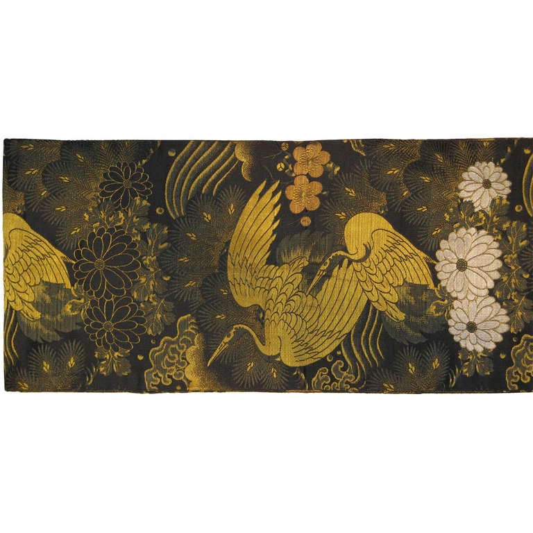 Antique Japanese maru obi from Kyoto. Patterned on both sides with heavy gold threading depicting cranes and the pine forest with plum blossoms and white chrysanthemums. It can be used as a table runner or as a wall hanging. Meiji period, circa