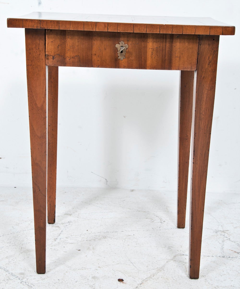 This charming and useful table was made in Italy during the first part of the 19th century. It has wonderful warm fruitwood inlays, a game board inlaid in the top and a drawer in the frieze. Standing on square tapered legs, this table is finished on
