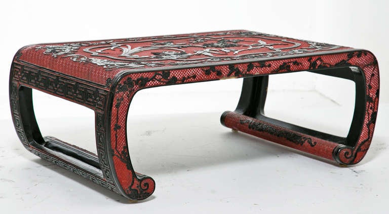 A very elegant late 19th century Chinese carved low table in two tones of cinnabar.   Featuring elegant carved flowers set on a highly carved red ground..  The table is a wonderful size and would serve nicely as a side table or coffee table.  We are