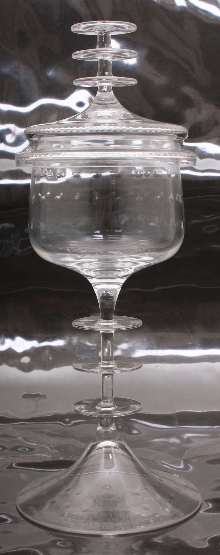 The molded clear glass circular wheel with cut design on flaring base and main body, three discs intersecting the stem; the finial comprised of same discs. This piece is from the R. F. Schwarz collection, one of the west coasts top designers for