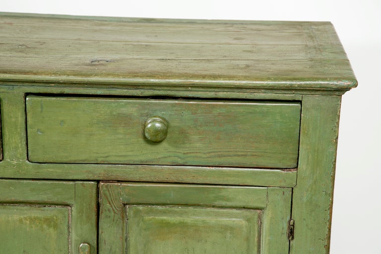 A nice provincial green painted Irish pine dresser base made during the first half of the 19th century.  A useful rustic piece with lots of character and storage.