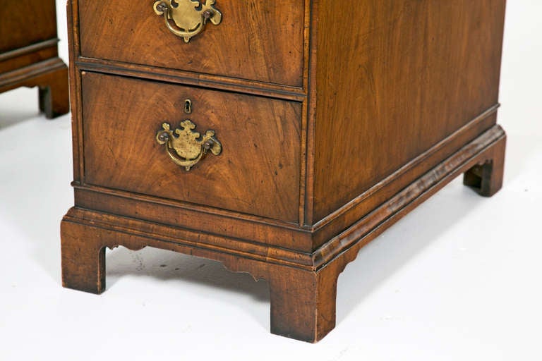 A late 19th century English Queen Anne style walnut double pedestal desk, with gold tooled leather top. Each pedestal has four graduated drawers and the center drawer over the knee hole. The Pedestals are raised on bracket feet. This piece is from