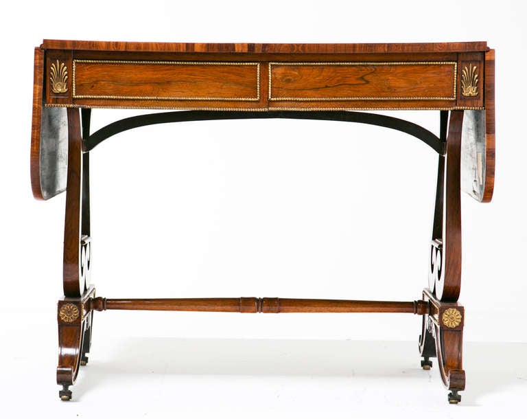 An exceptional early 19th Century English Regency Period rosewood and ambonyia cross banded sofa or writing table with ormolu mounts, circa 1810. The lyre supports have solid brass rods for the strings. The saber legs appear to have original