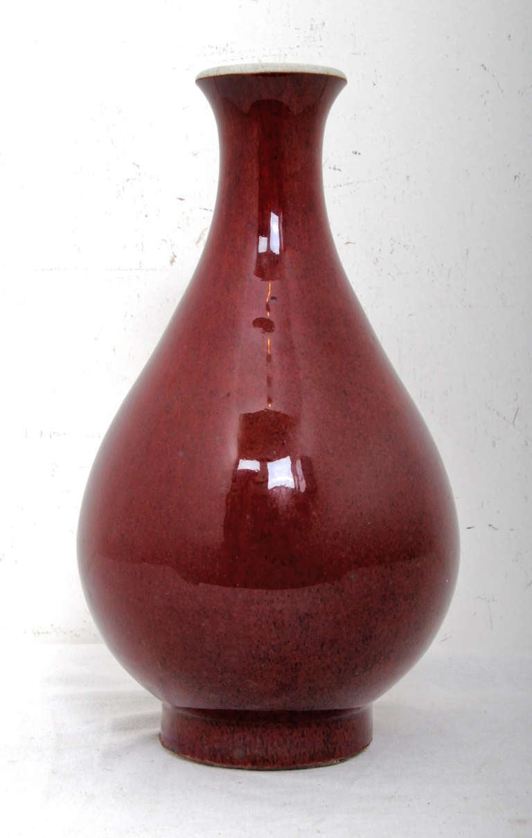 A very beautiful Ching dynasty oxblood (sang de bouef) vase or bottle made in China during the 19th century.  Exceptionally brilliant red glaze.  Elegant shape.  We think the edge of the top was reduced in size to remove a chip  We date this vase to