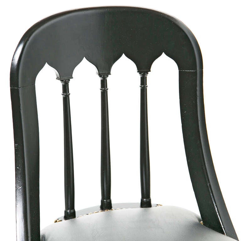 Classic early 19th century design chairs with an ebony finish and unusual arched Gothic arch inspired  backs.   We think these where made in Northern Europe.  The leather brass nail head upholstery is recent.   The frames have been tightened and