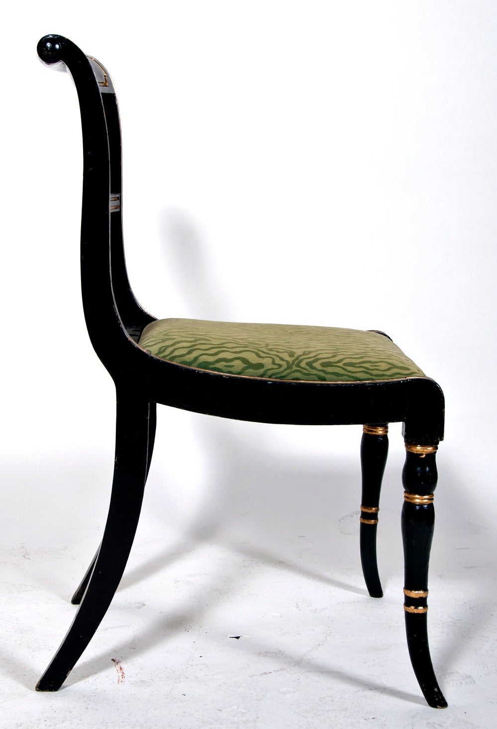 Chic and classic pair of original Regency Period ebonized and gilt side chairs.  These are probably carved from beechwood with cane seats.  The silk upholstery is slightly worn and probably later.  These chairs where made in England about 1810 and