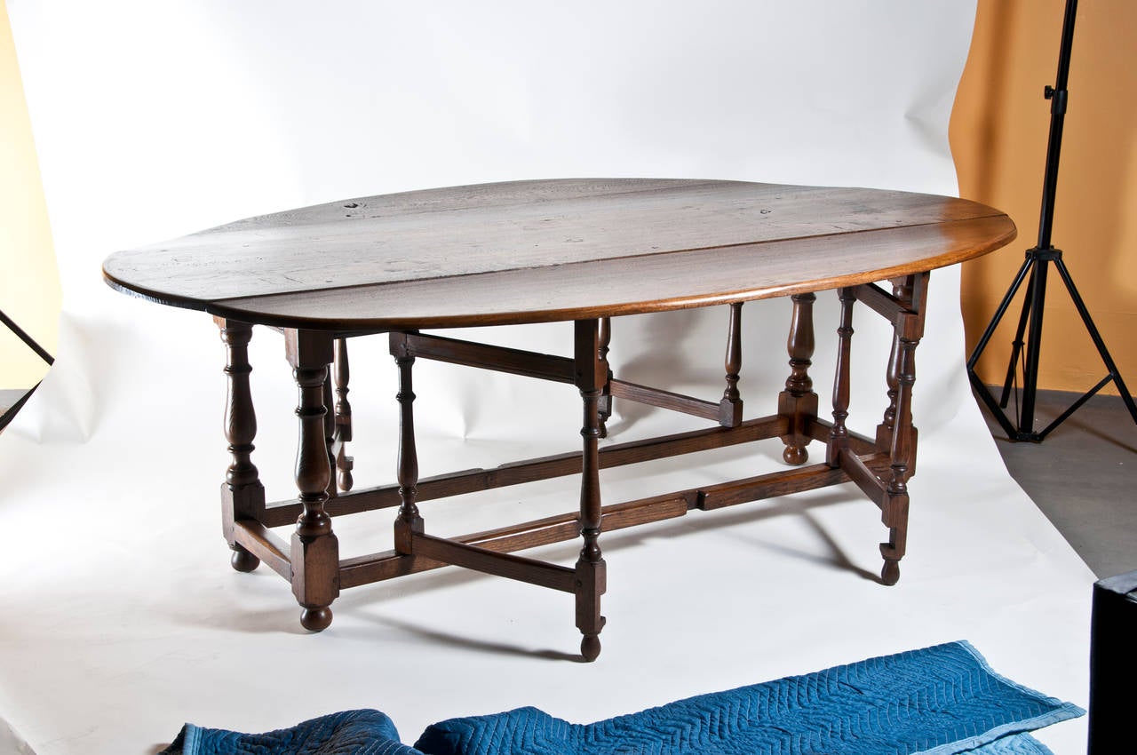 A massive hard to find English oak drop leaf table incorporating some antique elements, circa 1980. This table would easily seat 12. The style is first made in England about 1680. We think this dates to the 1980's. Wonderful old timber used in the