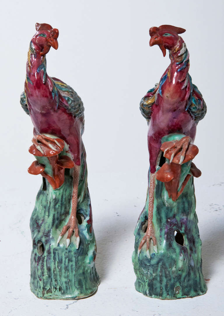 The facing standing polychromed phoenix birds on turquoise rock base with orange fungus.