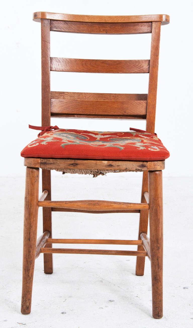 A charming set of four chestnut chairs made in France during the first part of the 19th century. These chairs have great color, wonderful tapestry seats and rare box mounted on the back to hold books and papers. From a good local collection.