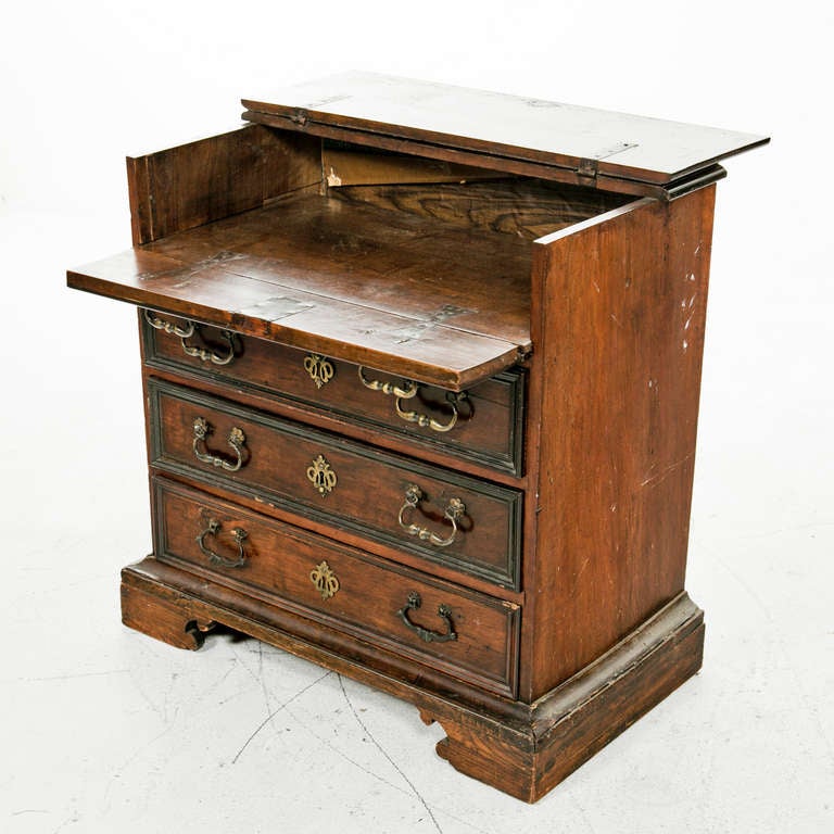 A handsome and small scaled Italian Baroque style butlers' or bachelors chest. The top drawer is meant to serve as a desk work surface. The bottom three drawers are for storage. Great old surface with some nice wear and evidence of age. The style