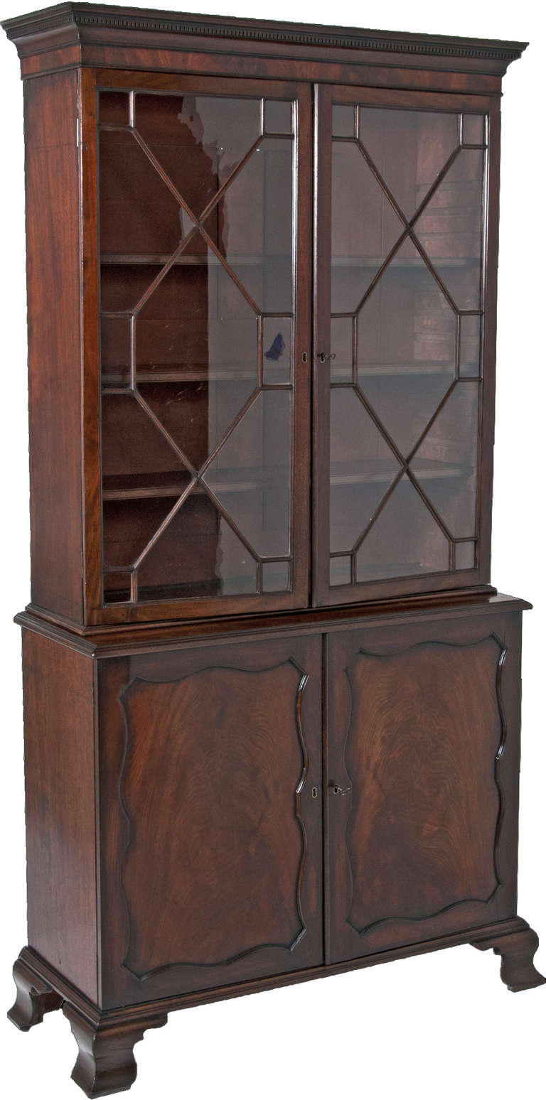 A classic Chippendale design mahogany bookcase or cabinet. We think this was made in England during the third quarter of the 18th century. Standing nicely on four ogee bracket feet. Nicely shaped cartouche panels centered on each cabinet door. The