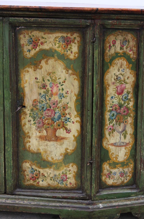 A wonderful green lacquered and painted Venetian cabinet/credenza made in Italy during the 18th century decorated with baskets and vases full of flowers. The painted sides substantially original. This piece has nice smaller scale with good