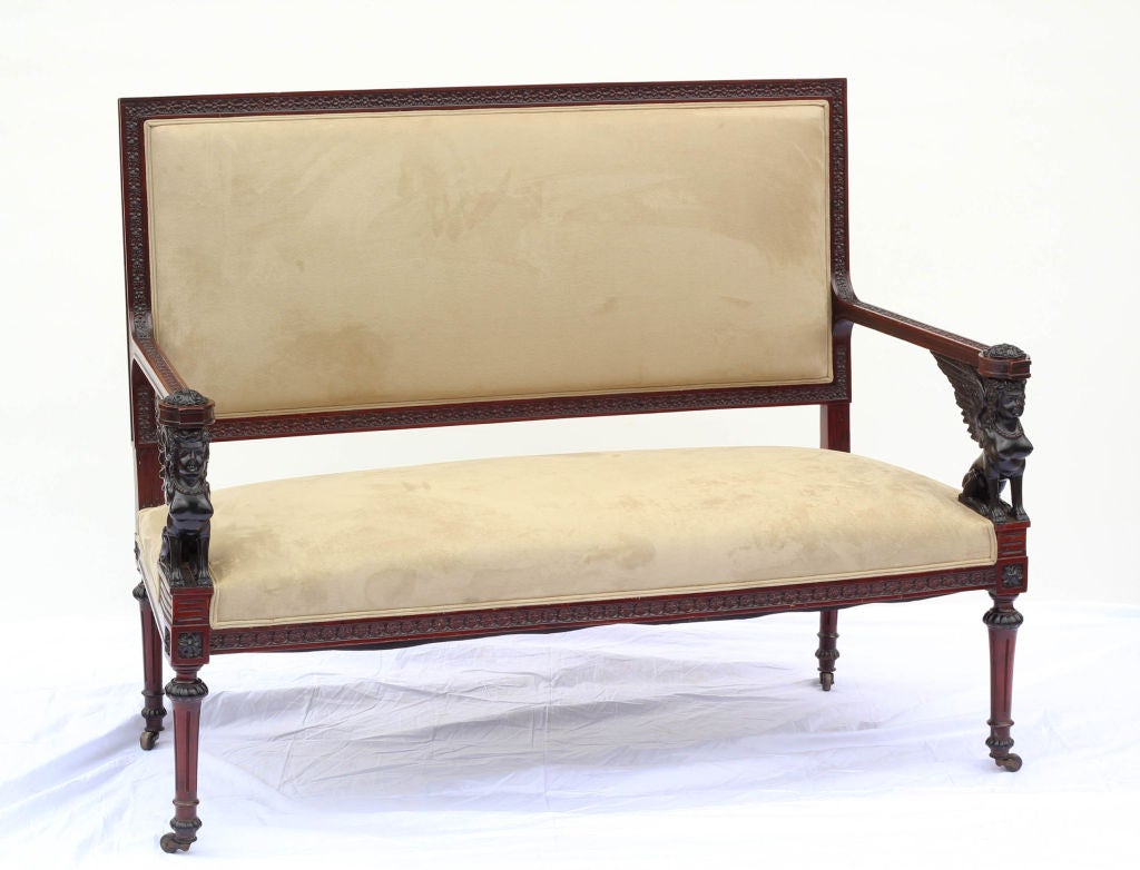 A Classic Empire style settee made in Europe late in the 19th century featuring ebonized carved wooden sphinxes.
