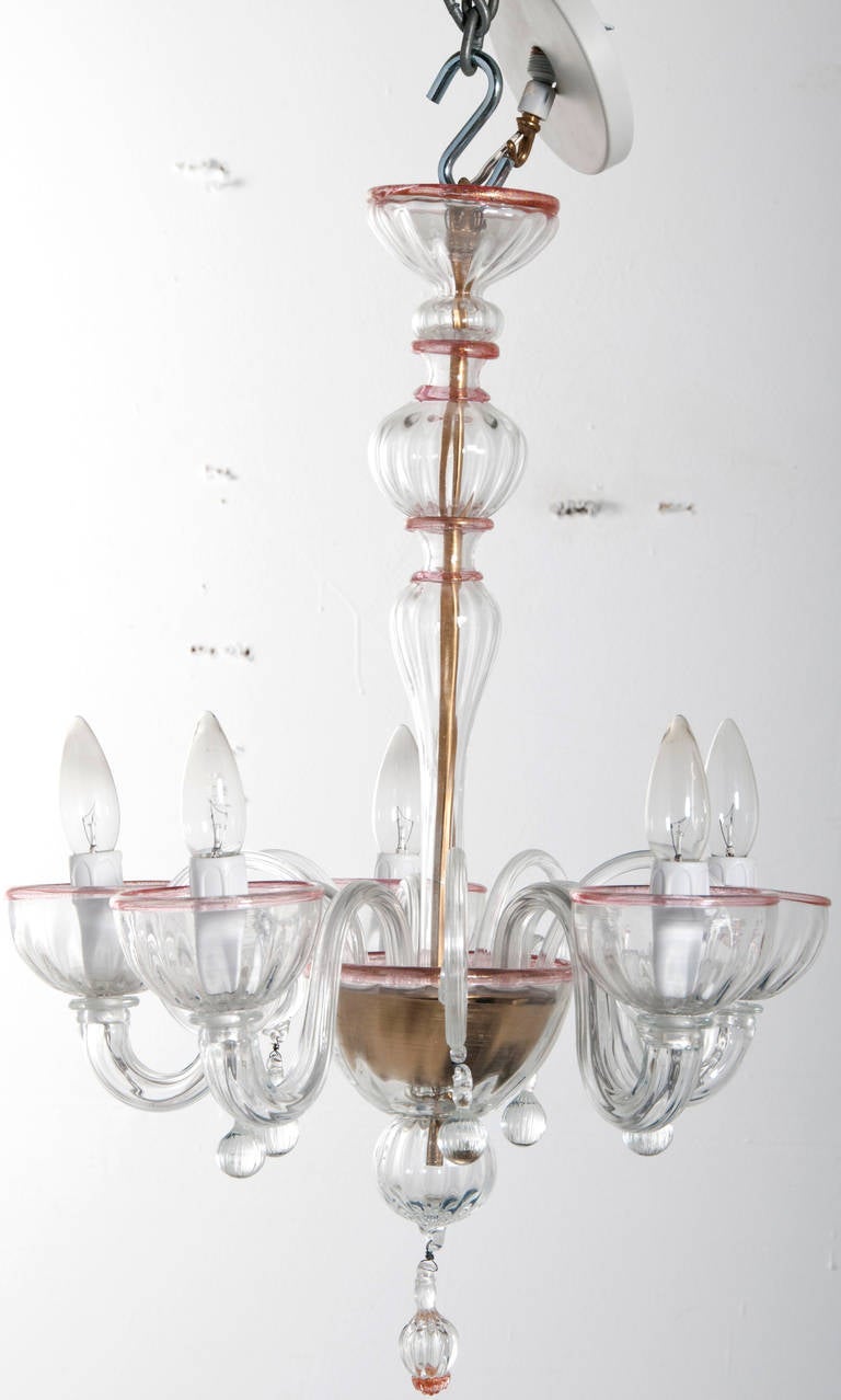 A small-scale vintage Murano clear glass chandelier highlighted with pink bands encircling the candle cups.  Very nice design typical from the 1960's.