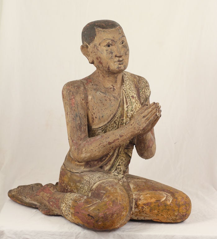 A large and elegant Burmese or Thai wooden carving of a Buddhist Monk decorated with paint, gesso, and inset small mirrors.