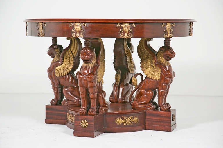 A heroic and large mahogany centre table made in Northern Europe during the second half of the 19th century, featuring seated large carved leo-gryphs with gilt highlights. Fantastic neoclassical design inspired by Roman & Greek antiquity.