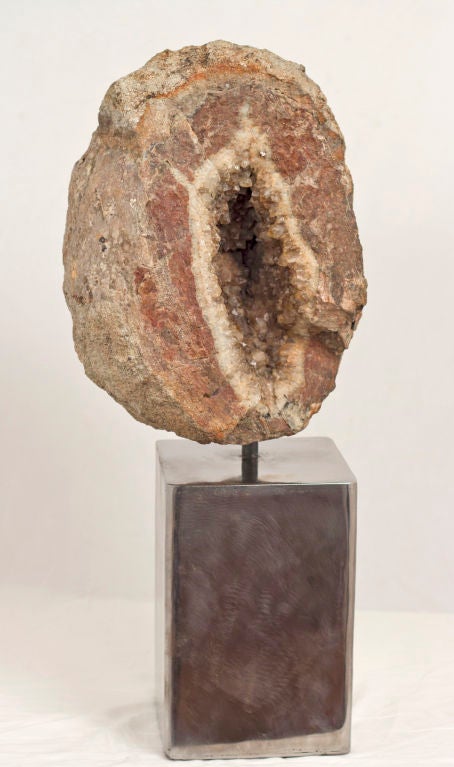 A large split geode on a custom polished steel stand.