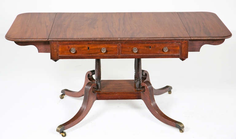 A very good early 19th century English Regency period sofa table/writing table made in circa 1815. Possibly Sottish or North country. Great reeded sabre legs with original brass casters. The top supported by four rope twist carved columns. This