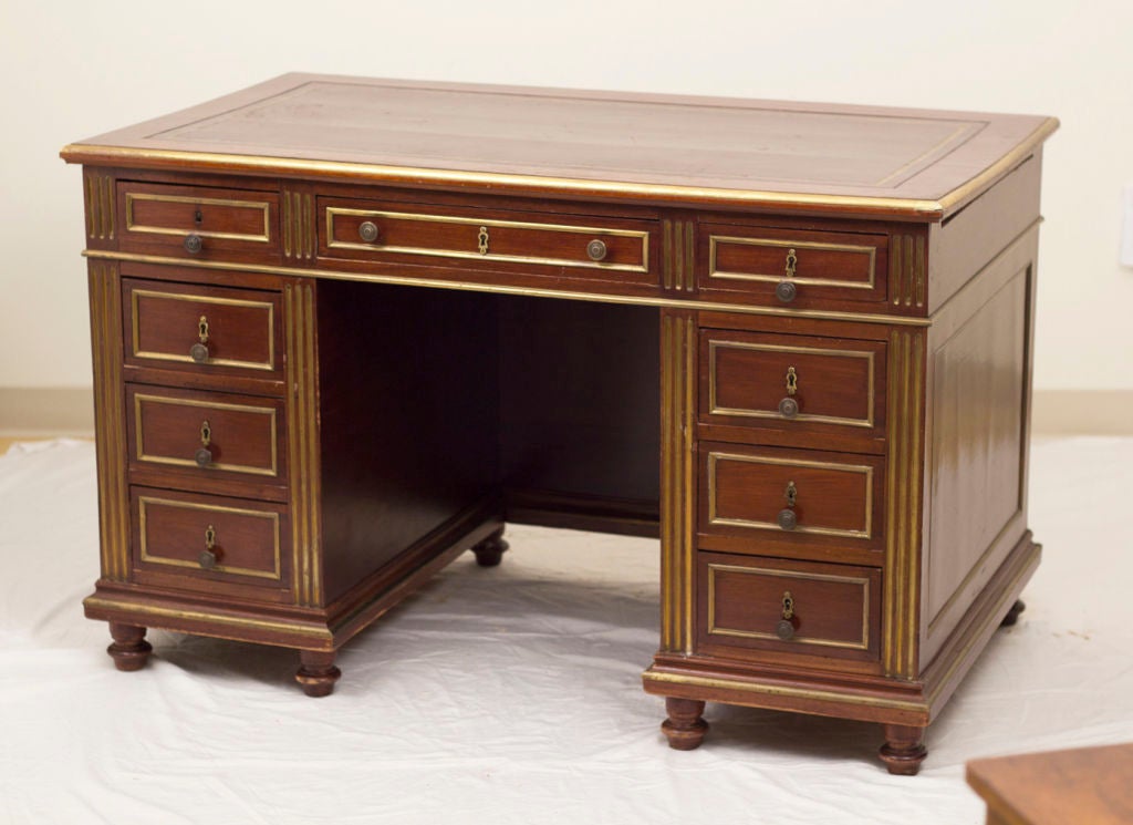 A nice 19th century French mahogany desk with brass banding to edges of writing surface and on drawer faces, additionally inlaid columns. The two pull-out work surfaces are inlaid with matching leather and are a particularly nice feature. We love