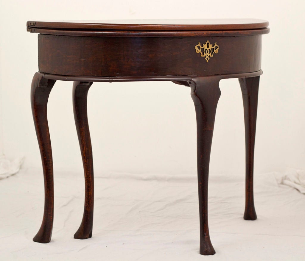 George II period oak demilune fold over tea table. A nice Provincial piece on graceful cabriole legs with triffid pad feet. The top folds open into a slightly oval tea table. The top also hinged to lift open to a storage well. 33" x 31"