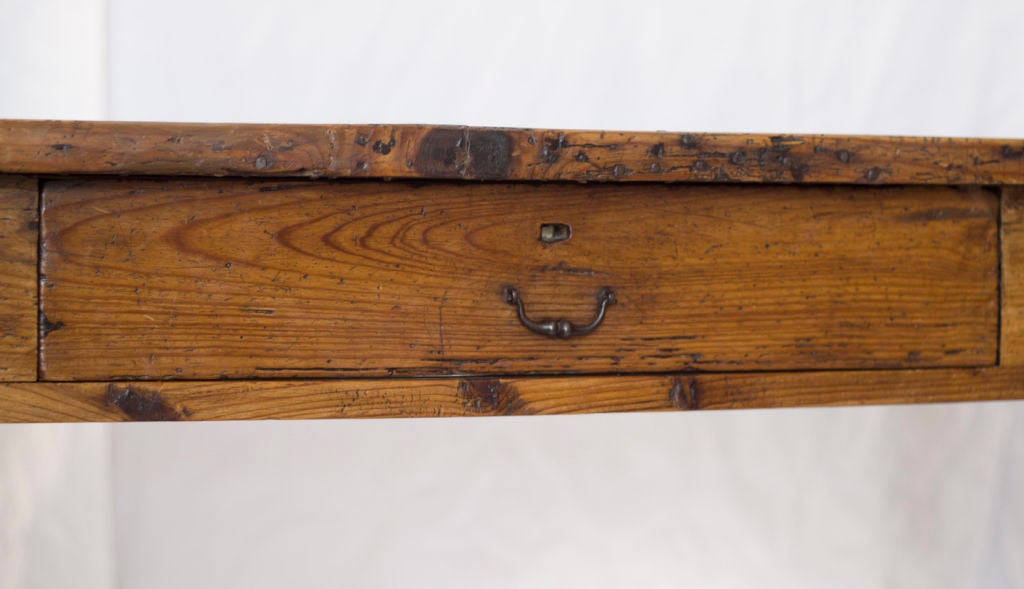 A nice old pine farm house table with single centered drawer.  Great old surface and color