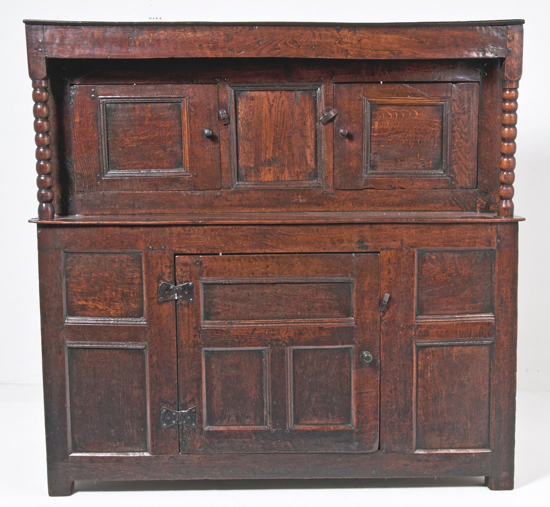 Wonderful early English court cupboard, circa 1630 of deep rich color and desirable small size. Court cupboards were the forerunner of the dresser and plate rack. The where used for food storage in the Inns and for storing Pewter. Bobbin turned