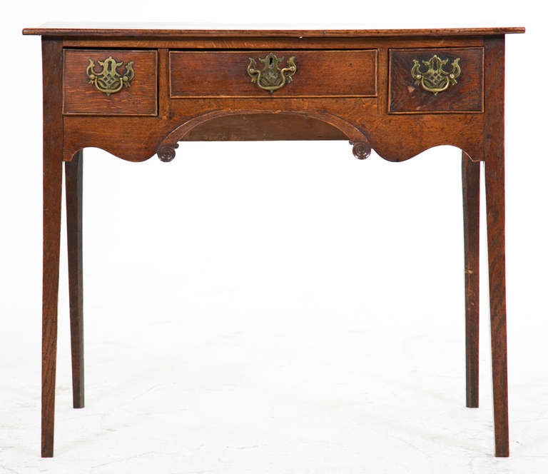 A Classic English country three drawers dressing table or "low boy" made, circa 1800. On square tapered legs with scalloped apron and pierced brass handles. Recently tightened and polished.