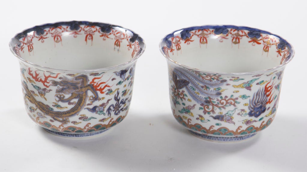 A nicely painted pair of Japanese Imari porcelain bowls or cache pots made during the 19th century.  Classic doucai decoration featuring a Phoenix and Dragon among jewels and scrolls.  The dragon symbolizes the emperor.  The phoenix symbolizes the