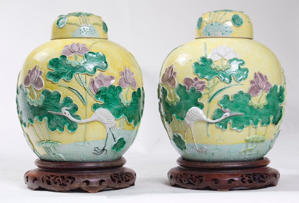 A great pair of Chinese porcelain covered ginger jars on rosewood stands.  The yellow ground color and the molded and raised decoration are unusual.  These are good sized and very decorative.