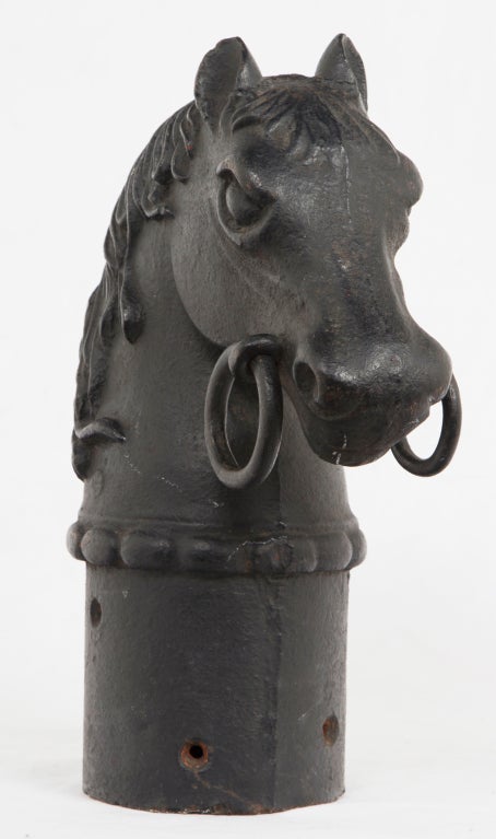 A charming and large cast iron hitiching post featuring a Horses head with a bit in its mouth.