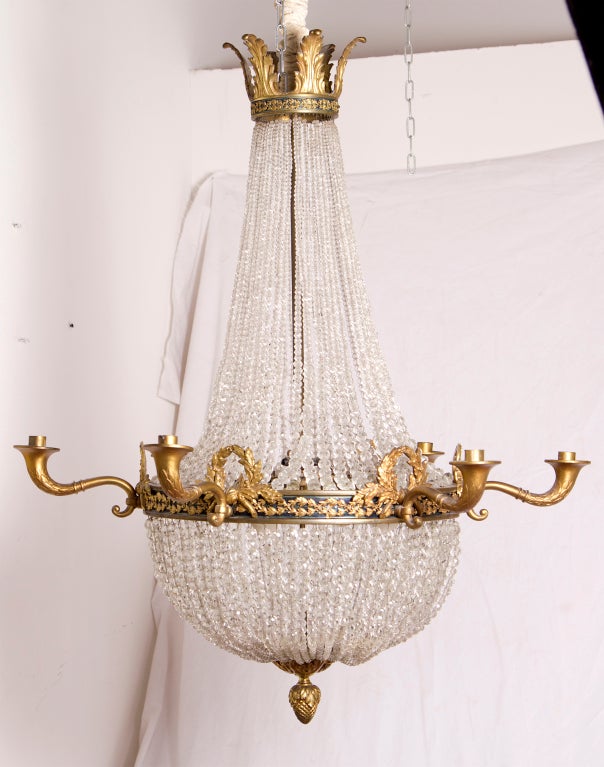 A very elegant and large beaded crystal chandelier with ormolu mounts done in the Empire style. Featuring swags of laurel and victory wreaths with candle arms shaped a cornucopia. The interior features four lights. The 6 arms are for candles but
